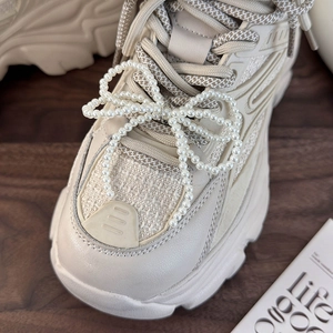 Detail of beaded pearl bow charm attached to a cream chunky sneaker shoe lace