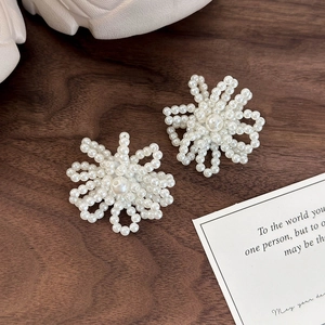 Detailed view of handmade white faux pearl flower shoe charms on a rustic wooden table