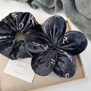 Elegant black velvet scrunchie set with white bow and polka dot patterns on a tray