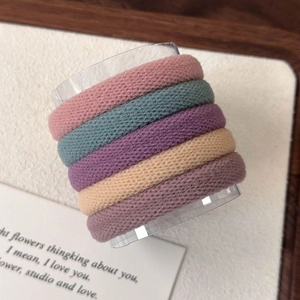 Detail van vijf dikke elastische haarbanden in Morandi-kleuren op een standaard