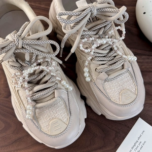 Dettaglio di fiocco di perle e ciondoli in cristallo rosa su sneaker platform