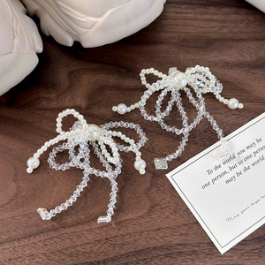 Detailed view of handmade crystal pearl bow shoe charms on a white lace lace sneaker