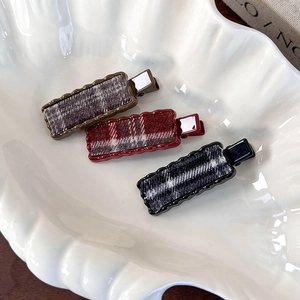 Lot de trois barrettes vintage à carreaux marron, rouge et gris sur un plateau en céramique