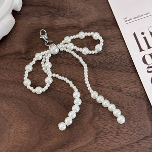 Detail of handcrafted white pearl bow shoe buckle charm with silver lobster clasp on wood