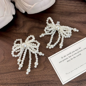 Detail of elegant pearl bow shoe charms with dangling tassels on white sneakers