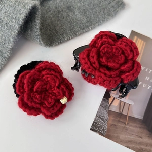 Détail du chouchou et de la pince rose en tricot rouge avec petite étiquette dorée