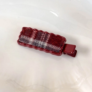 Détail de l'incrustation en tissu à carreaux rouges sur barrette vintage à bords ondulés