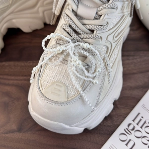 Detail of beaded pearl bow decoration on stylish off-white platform sneakers