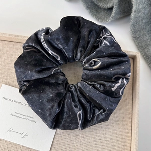 Macro shot of black velvet scrunchie featuring white bow and polka dot patterns