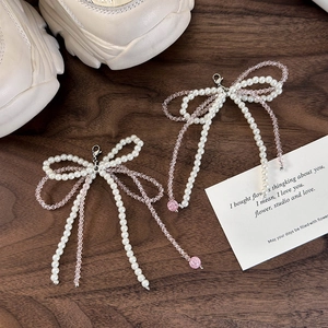 Dettaglio dei ciondoli per scarpe a fiocco con perle bianche e perline di cristallo rosa