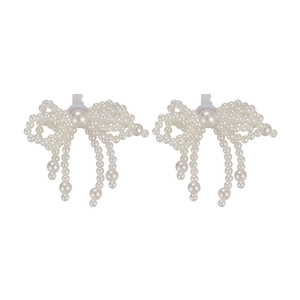 Detail of white pearl bow shoe charms with elegant hanging tassels and secure clips