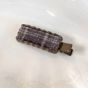 Gros plan détaillé d'une pince à cheveux vintage à carreaux marron et bords ondulés