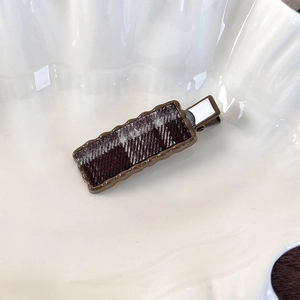 Détail d'une pince à cheveux vintage à carreaux avec bords ondulés et clip métallique