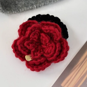 Détail macro d'un chouchou rose rouge tricoté main avec petite étiquette dorée