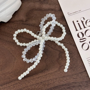 Detail of handcrafted beaded bow shoe charm featuring white pearls and crystal beads