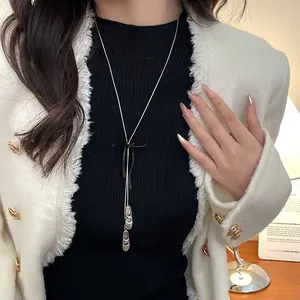 Detail of silver ballet shoe pendants and black bow on a long sweater chain necklace