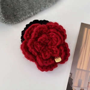 Détail d'une fleur de rose tricotée rouge faite main avec étiquette dorée chic