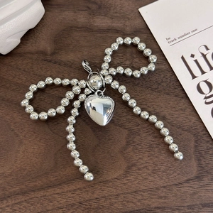 Silver beaded bow charm with a smooth heart pendant on a stylish lobster clasp