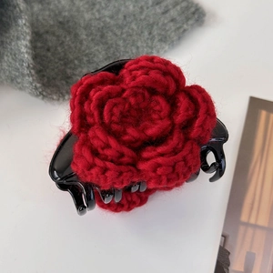 Détail macro d'une rose en laine rouge tricotée à la main sur une pince à cheveux noire