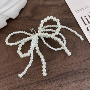 Detailed view of handcrafted pearl bow shoe charm with a silver lobster clasp