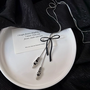 Elegant silver snake chain necklace featuring black bow and ballet flat shoe pendants