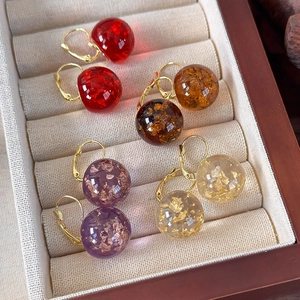 Orecchini a sfera in resina con foglia d'oro nei colori rosso, ambra e viola in una scatola