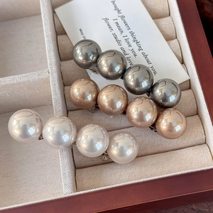 Trois grandes barrettes à perles synthétiques en gris, champagne et crème sur présentoir