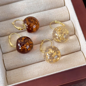 Dettaglio orecchini vintage a sfera in resina con foglia oro in marrone e beige