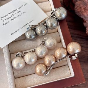 Détail de grandes barrettes à perles en couleurs argent, crème et champagne doré