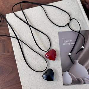 Detail of red and black heart pendant necklaces with adjustable black cord on wooden table