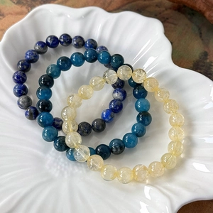 Three natural colorful 8mm stone beaded bracelets displayed on a white shell plate