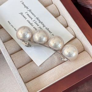 Détail macro de grandes perles sur une barrette à ressort argentée avec boîte cadeau