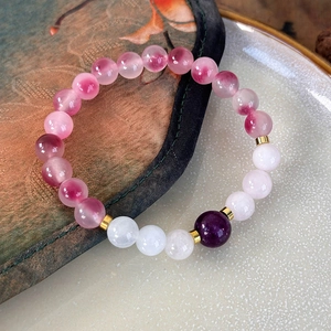 Detail of handmade beaded bracelet with gradient pink and purple natural stones and gold spacers