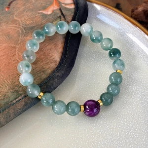 Macro detail of handmade stone beaded bracelet with green jade and purple center bead