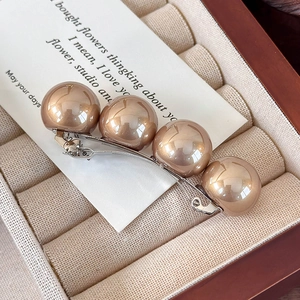 Vue détaillée de grandes perles champagne sur une barrette à ressort en argent raffinée