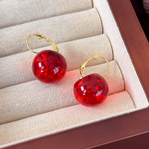 Dettaglio orecchini a sfera in resina color ambra con foglie d'oro e ganci dorati