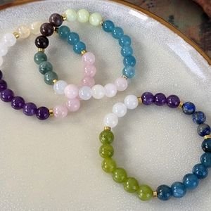 Detailed macro view of colorful stone beaded bracelets with golden spacer accents
