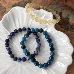Close-up of natural citrine lapis lazuli and apatite beaded bracelets on a shell plate