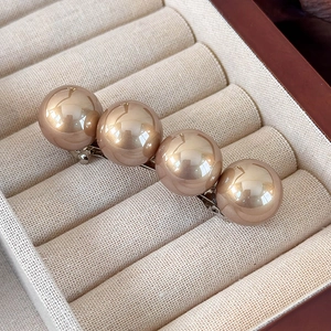 Détail de quatre perles dorées champagne sur une pince à cheveux argentée chic