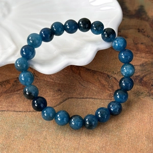 Macro detail of deep blue natural stone beaded bracelet with polished cat eye texture