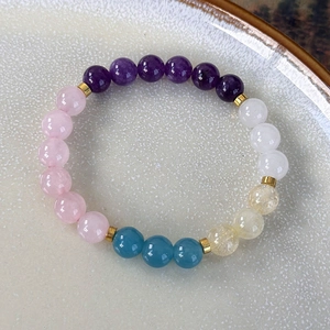 Detail of colorful crystal beaded bracelet with purple, pink and blue stones and gold spacers