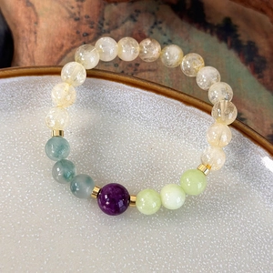 Macro shot of handmade beaded bracelet with colorful natural stones on white porcelain plate