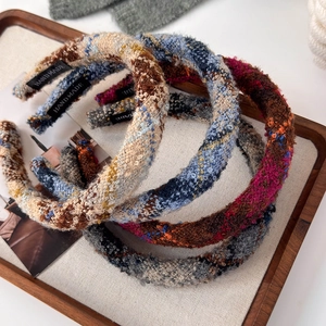 Detailed shot of tweed wide headbands featuring handmade labels and woven texture
