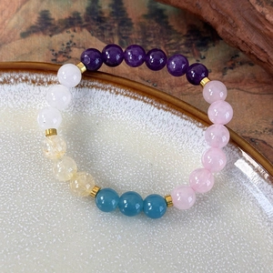 Macro detail of colorful crystal beaded bracelet with gold spacers on ceramic plate