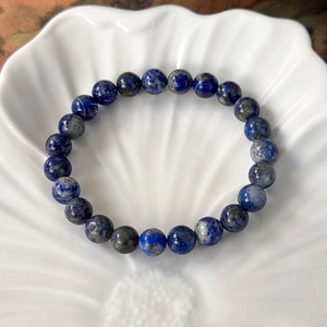 Macro shot of natural lapis lazuli beaded bracelet with gold pyrite flecks on white shell