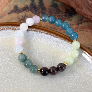 Detail of colorful beaded bracelet with gold spacers on vintage ceramic dish
