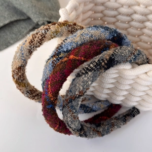 Detailed close-up of multi-colored tweed knit headbands arranged on a woven basket rim