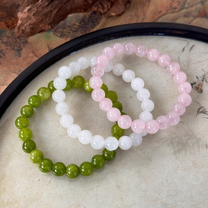 Detailed shot of pink, white, and green stone beaded bracelets in a classic tray