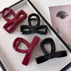 Set of four minimalist red and black bow hair claws with glossy finish on display tray