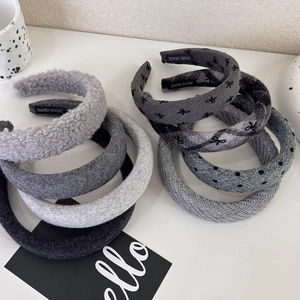 Close-up of various grey knitted and plush headbands with dotted patterns and bows